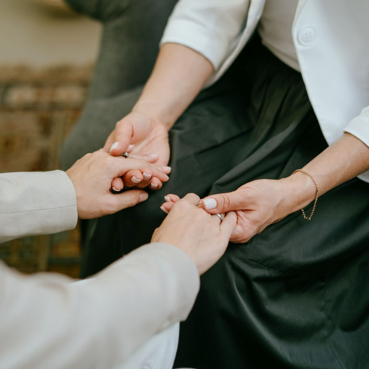 Two women are holding hands while sitting on a couch