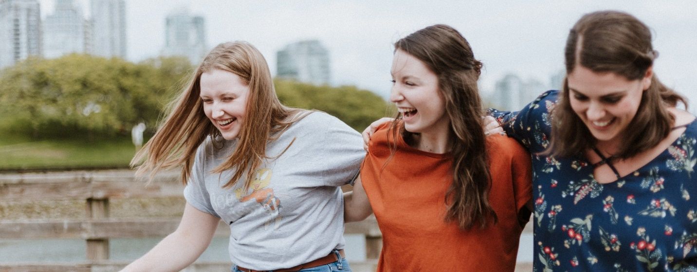 Three young women are standing next to each other and laughing.