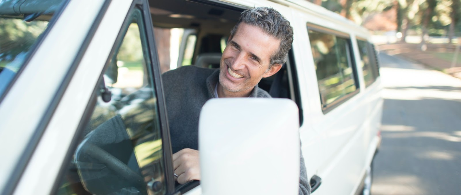 A man is looking out of the window of a white van.