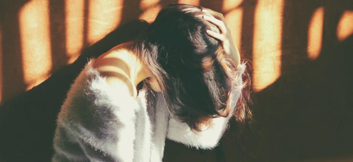 A woman is sitting down with her head in her hands.