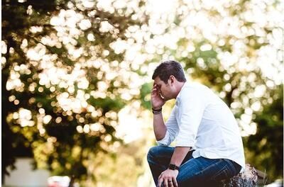 A man is sitting on a rock with his head in his hands. A man is sitting on a rock with his head in his hands.