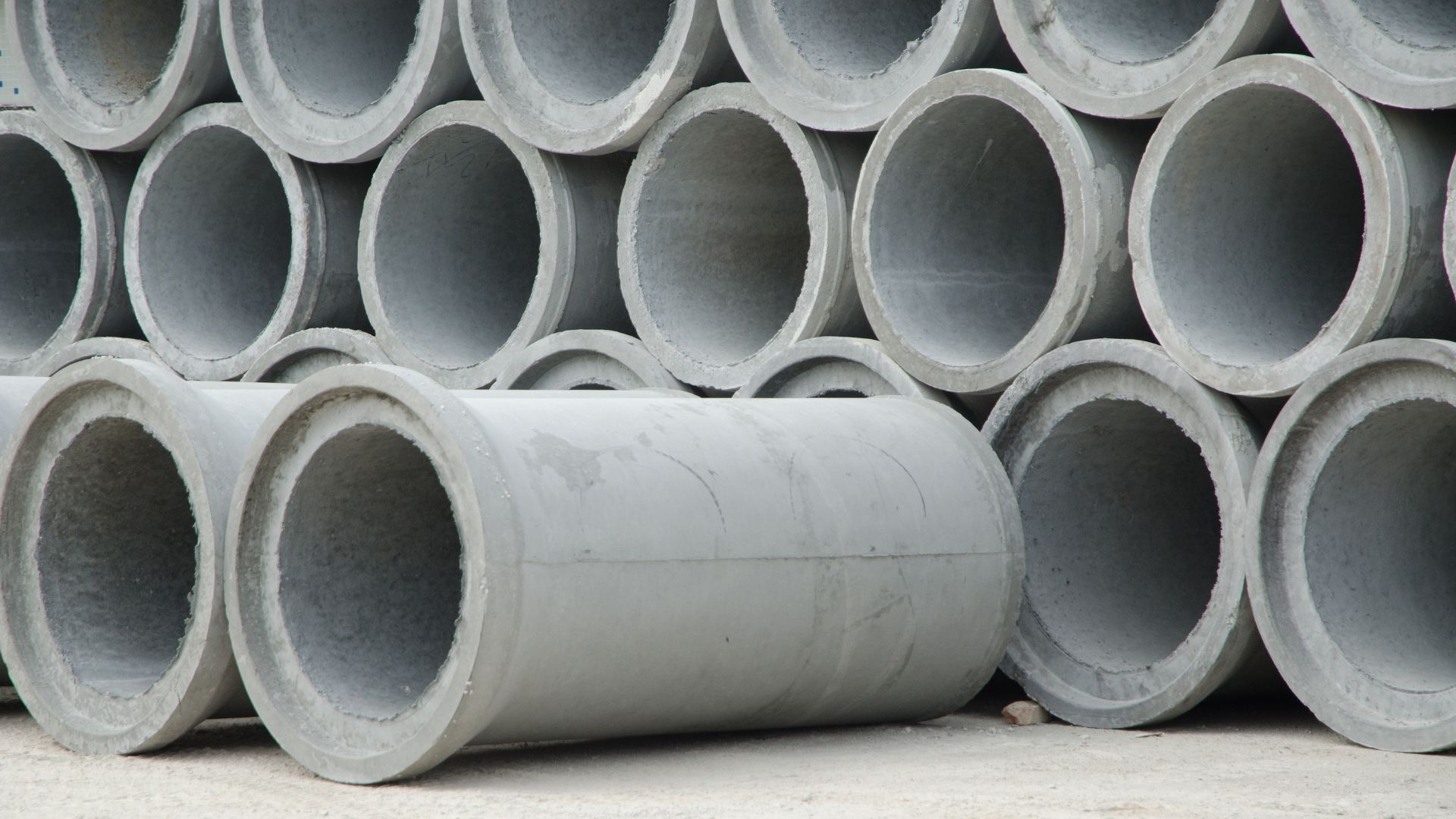 Gray concrete pipes stacked in a pile, ready for use.