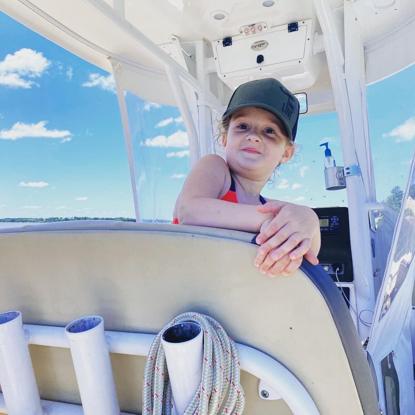 A little girl wearing a hat is sitting on a boat