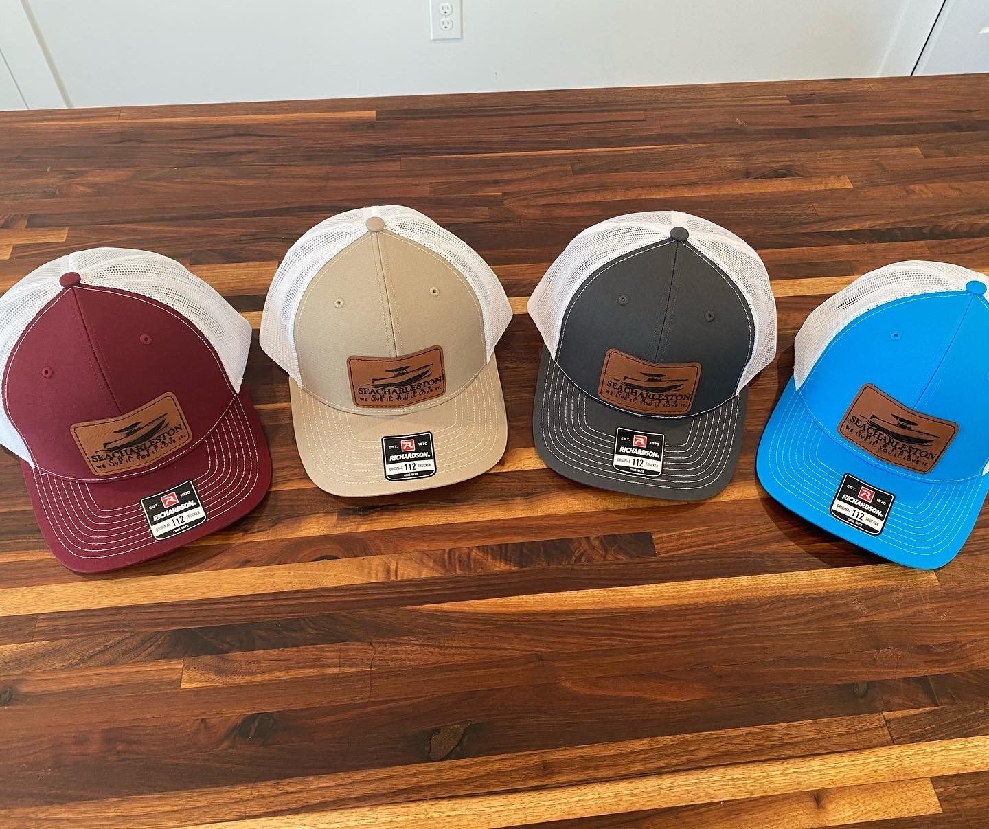 Four baseball caps are sitting on a wooden table.