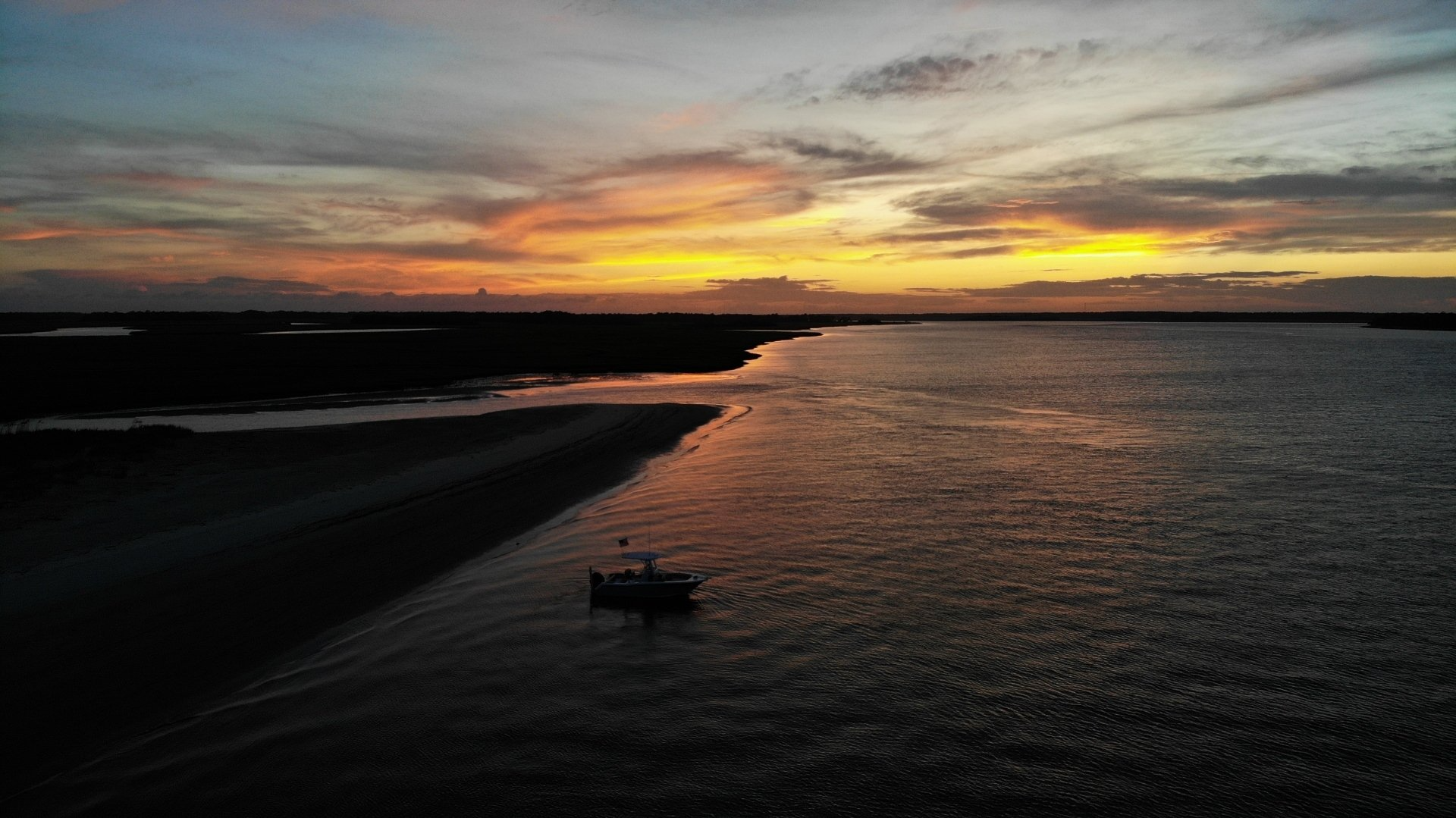 An aerial view of a boat in the water at sunset.