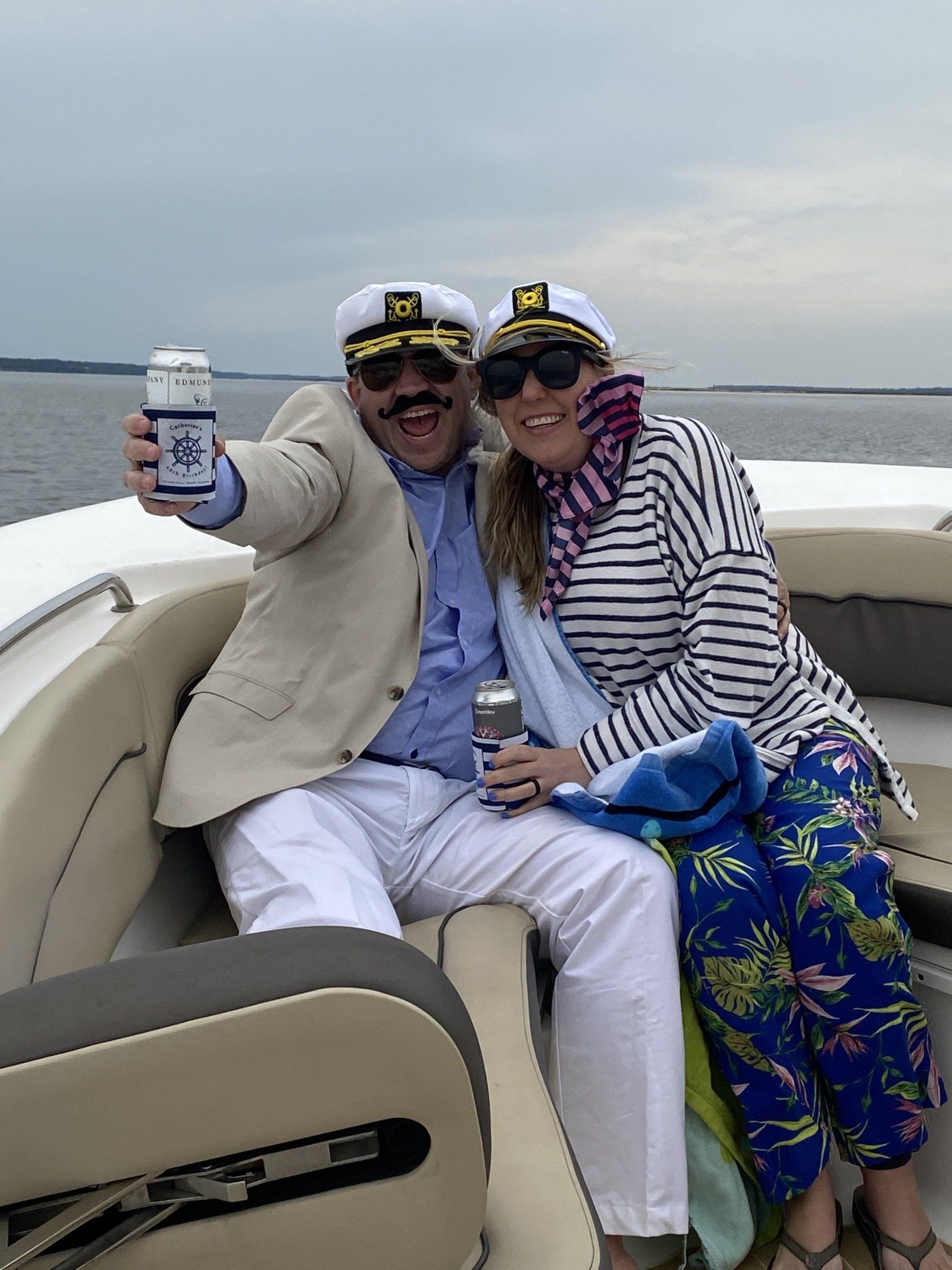 A man and a woman are sitting on a boat holding cans of beer.