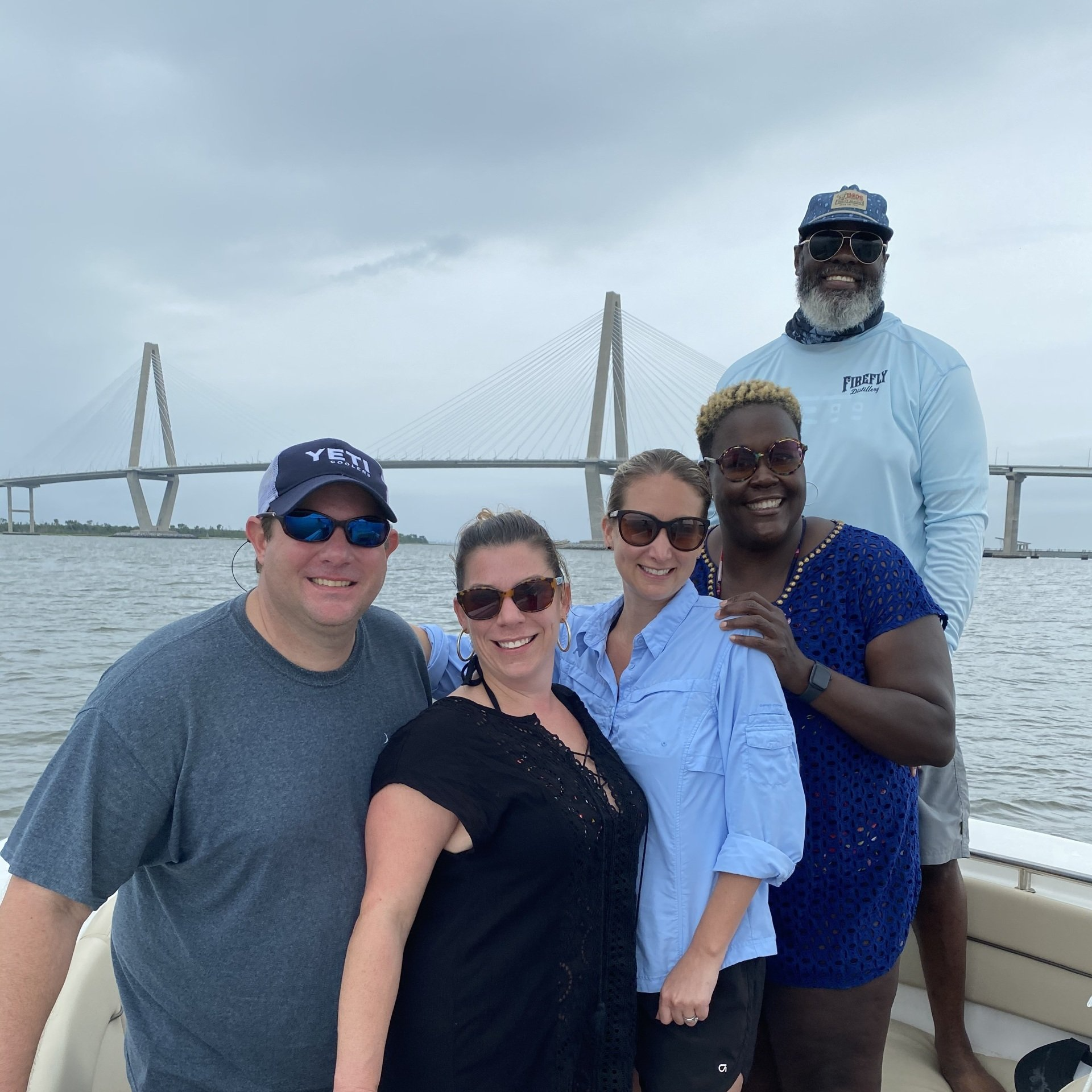A group of people posing for a picture on a boat with a bridge in the background