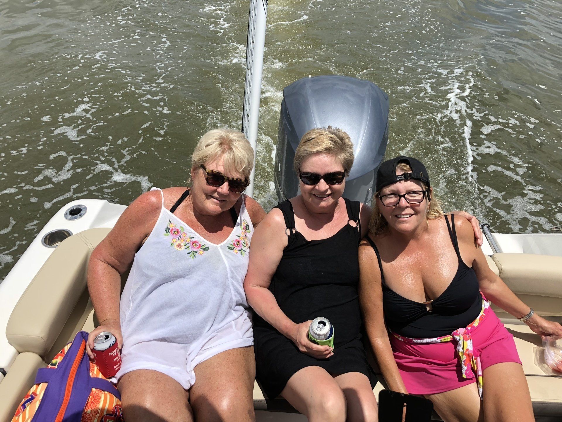 Three women are sitting on a boat in the water.