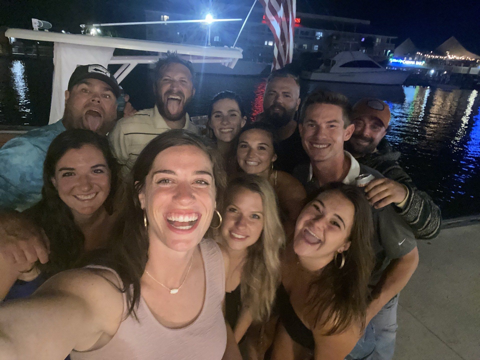 A group of people are posing for a selfie in front of a body of water.