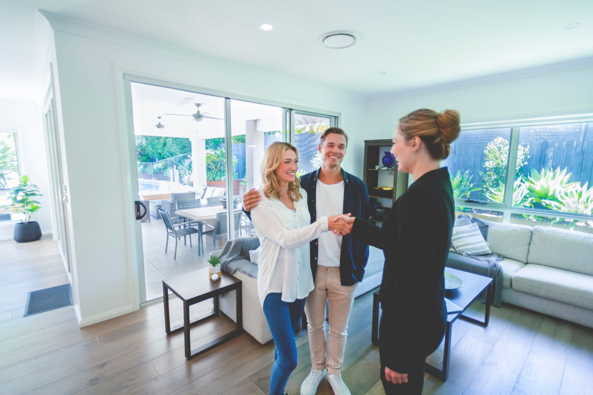 A woman is shaking hands with a man and woman in a living room.