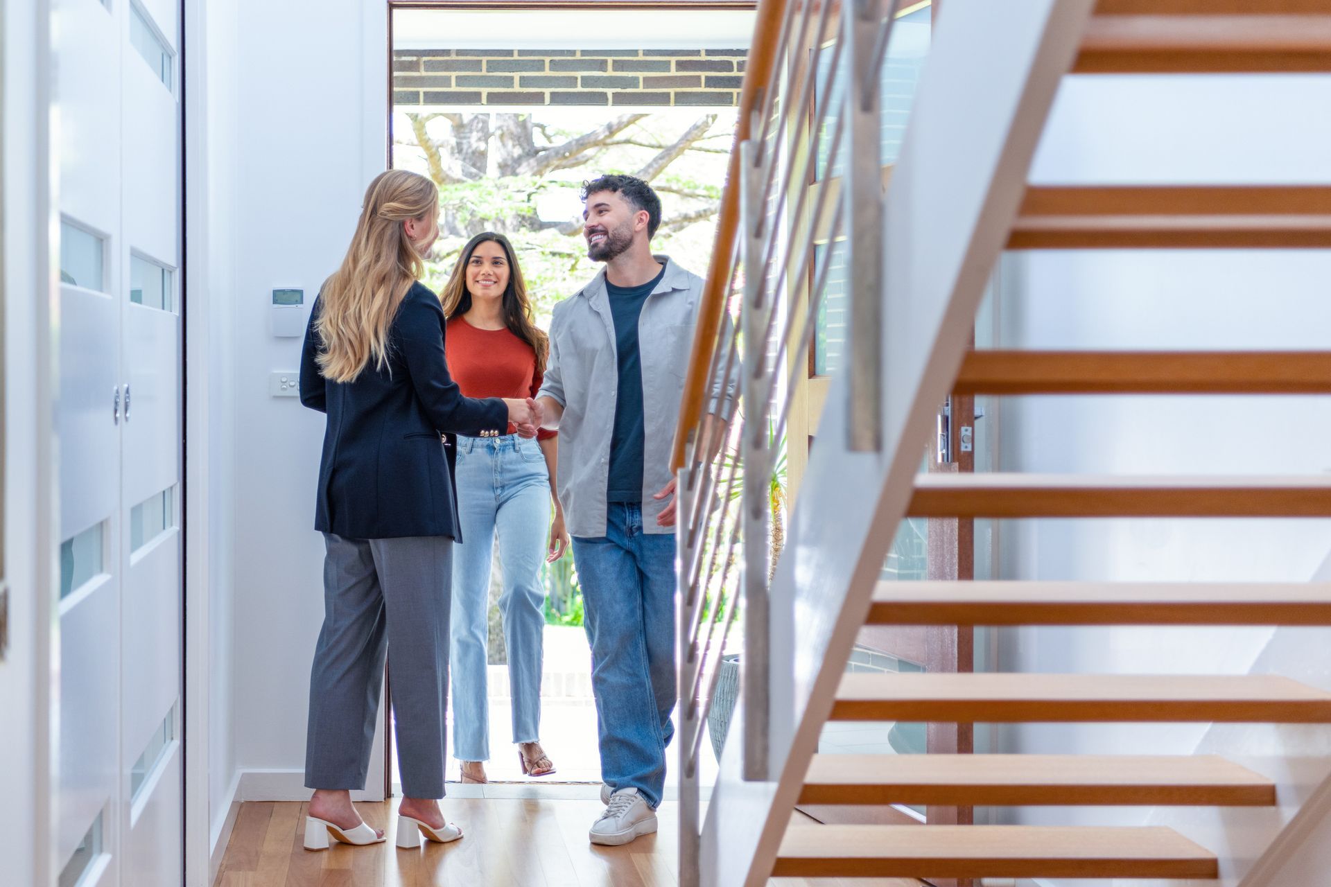 A group of people are standing in a hallway talking to each other.