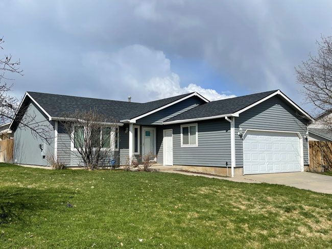 A gray house with a black roof and a white garage door.