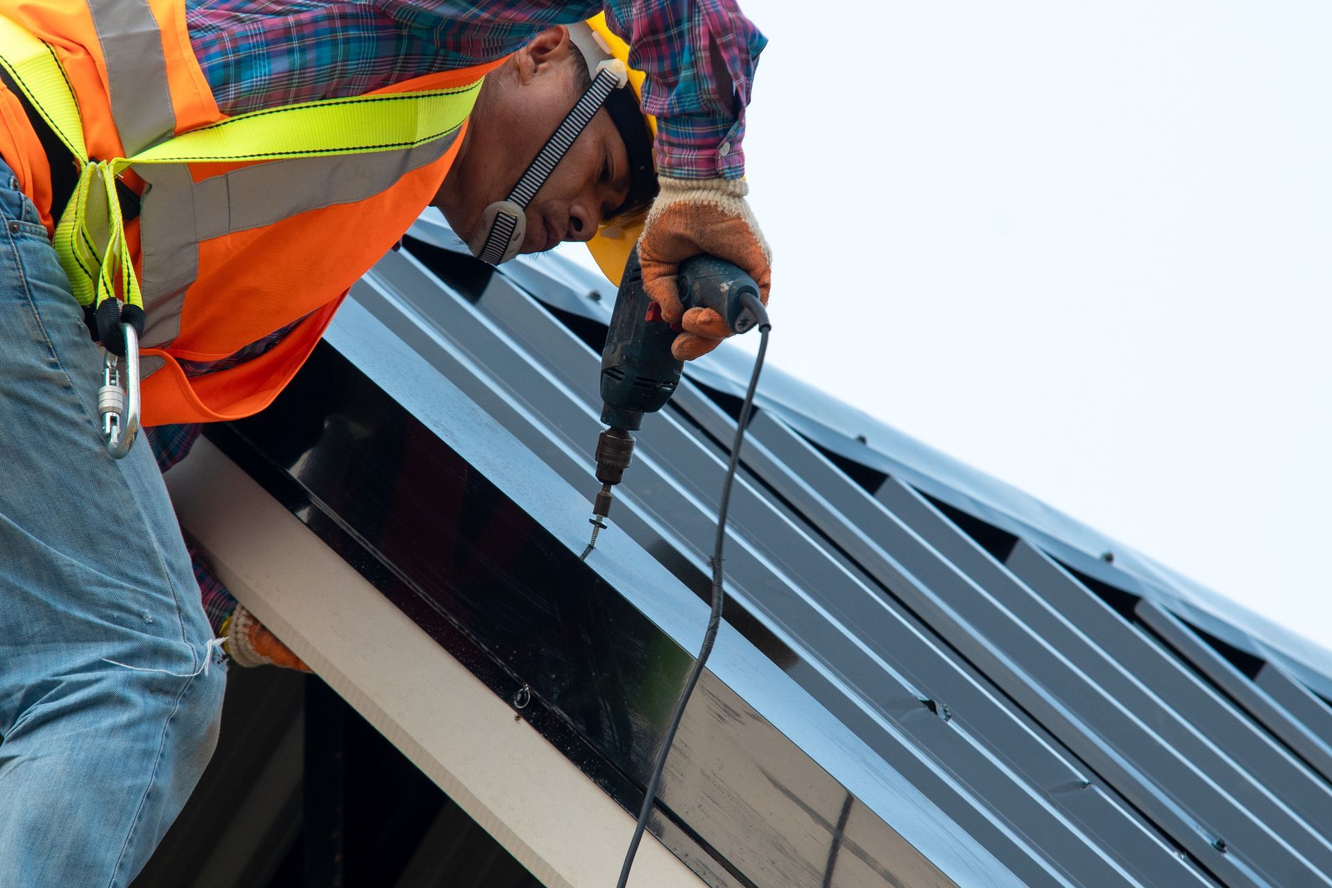 A technician from 20/20 Exteriors is at work installing metal roof replacement in Spokane, WA