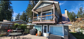 A house with a large deck and a table and chairs in front of it.