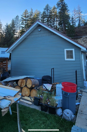 A pile of logs is sitting in front of a house.