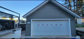 A garage with a white garage door and a truck parked in front of it.