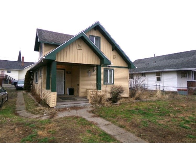 A small house with a green roof and a car parked in front of it