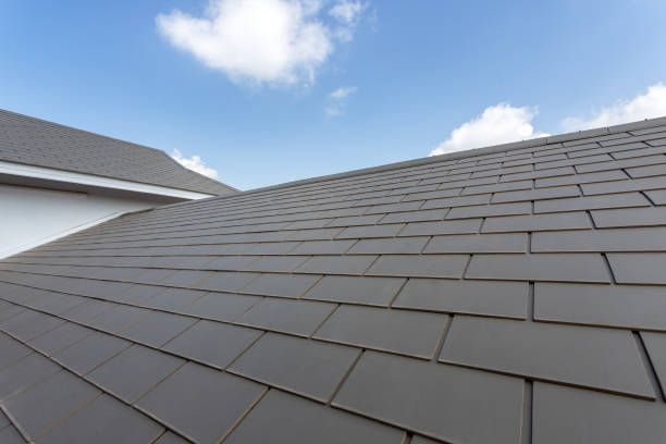 Modern gray roof shingles under clear blue sky on residential house.