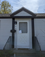 A white house with a brown roof and a white door.