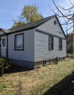 A small house with a lot of windows is sitting in the middle of a grassy field.
