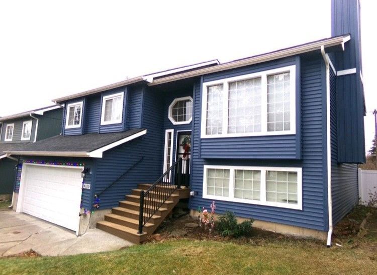 A blue house with a white garage door and stairs