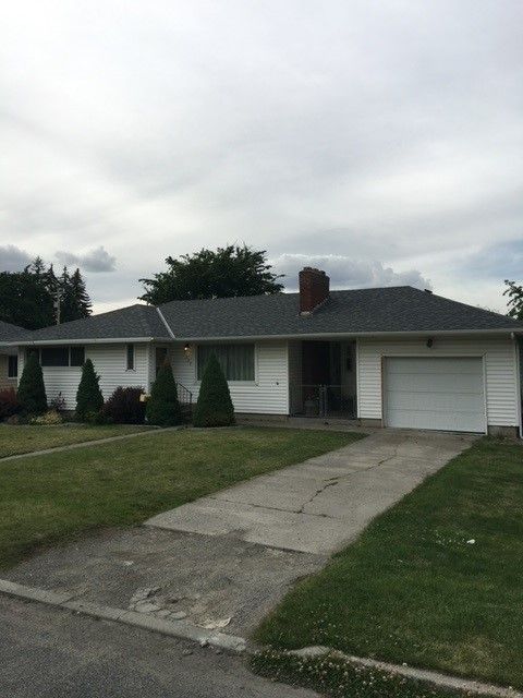 A white house with a gray roof and a white garage door