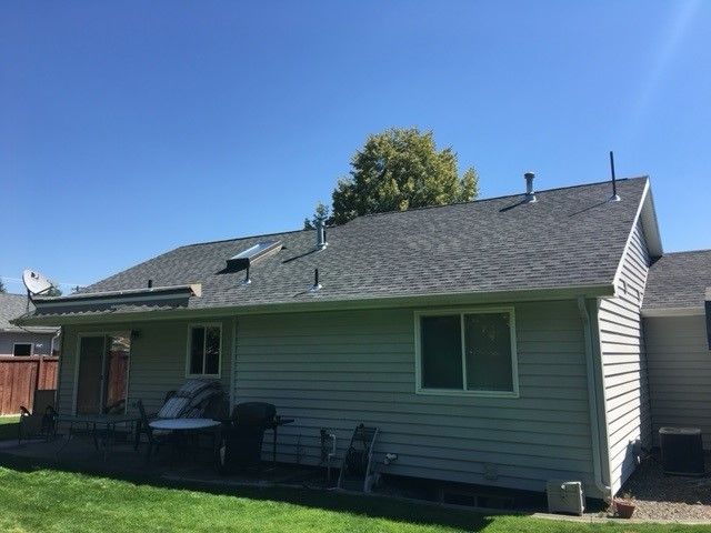 The back of a house with a gray roof and a patio area.