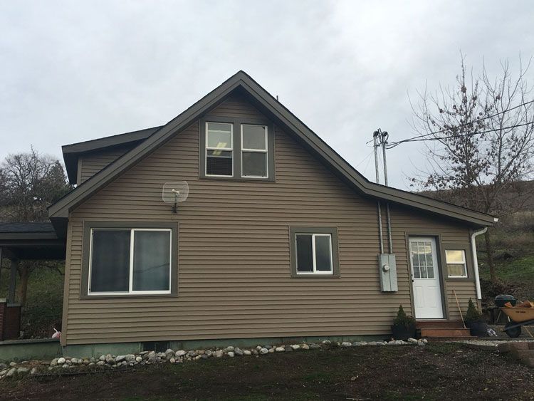 A brown house with a roof and a lot of windows
