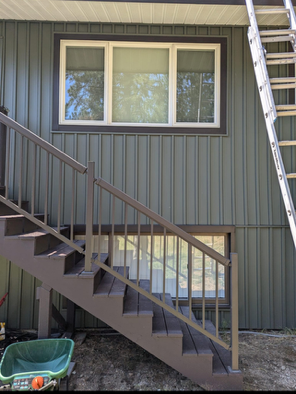 A green wheelbarrow sits next to a set of stairs