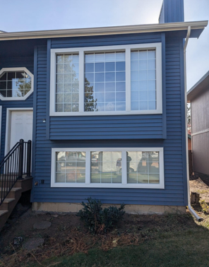 A blue house with white windows and a staircase.