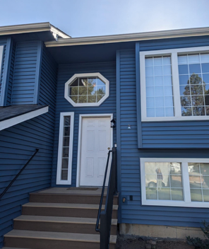 A blue house with stairs leading up to the front door