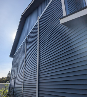 A large blue barn with a blue siding and a blue sky in the background.