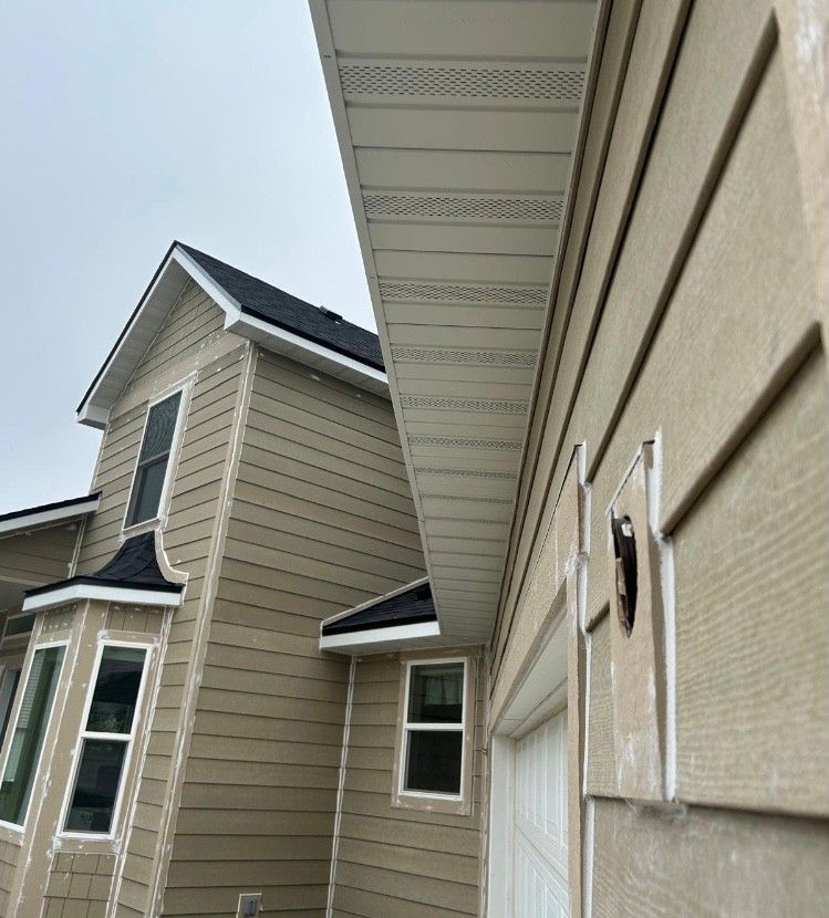 Tan house exterior with white trim, soffit, and siding. Cloudy sky.