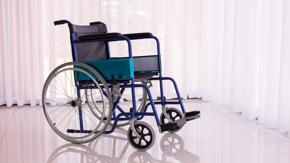 A blue wheelchair (an example of durable medical equipment) is sitting in a room next to a window.