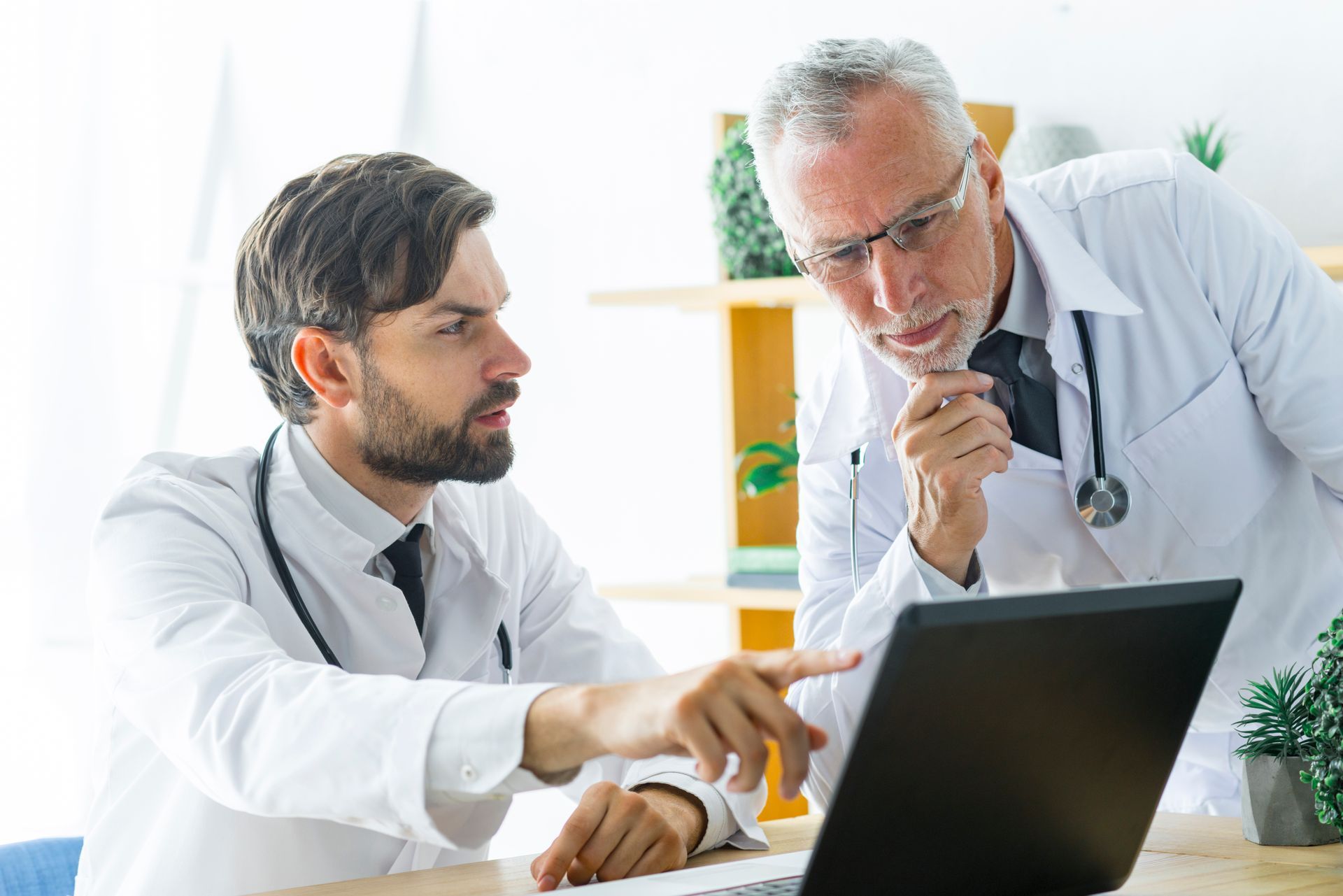 Two doctors are looking at a laptop computer together.