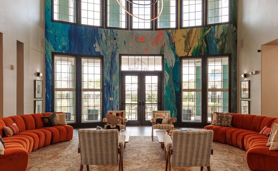 a living room with orange couches and chairs and a large wall mural