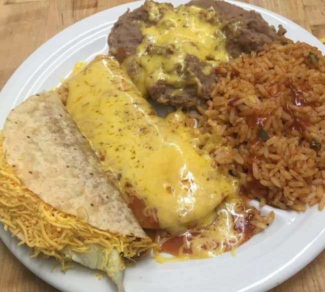 A white plate topped with tacos rice and beans