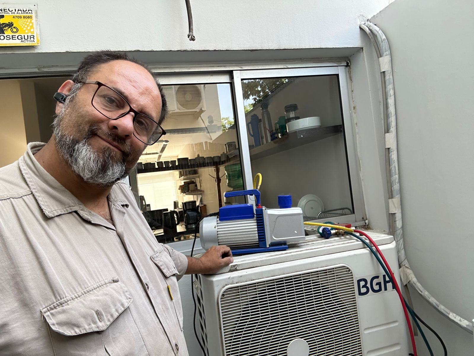 Persona utilizando un destornillador para reparar una unidad de aire acondicionado blanca montada en la pared.