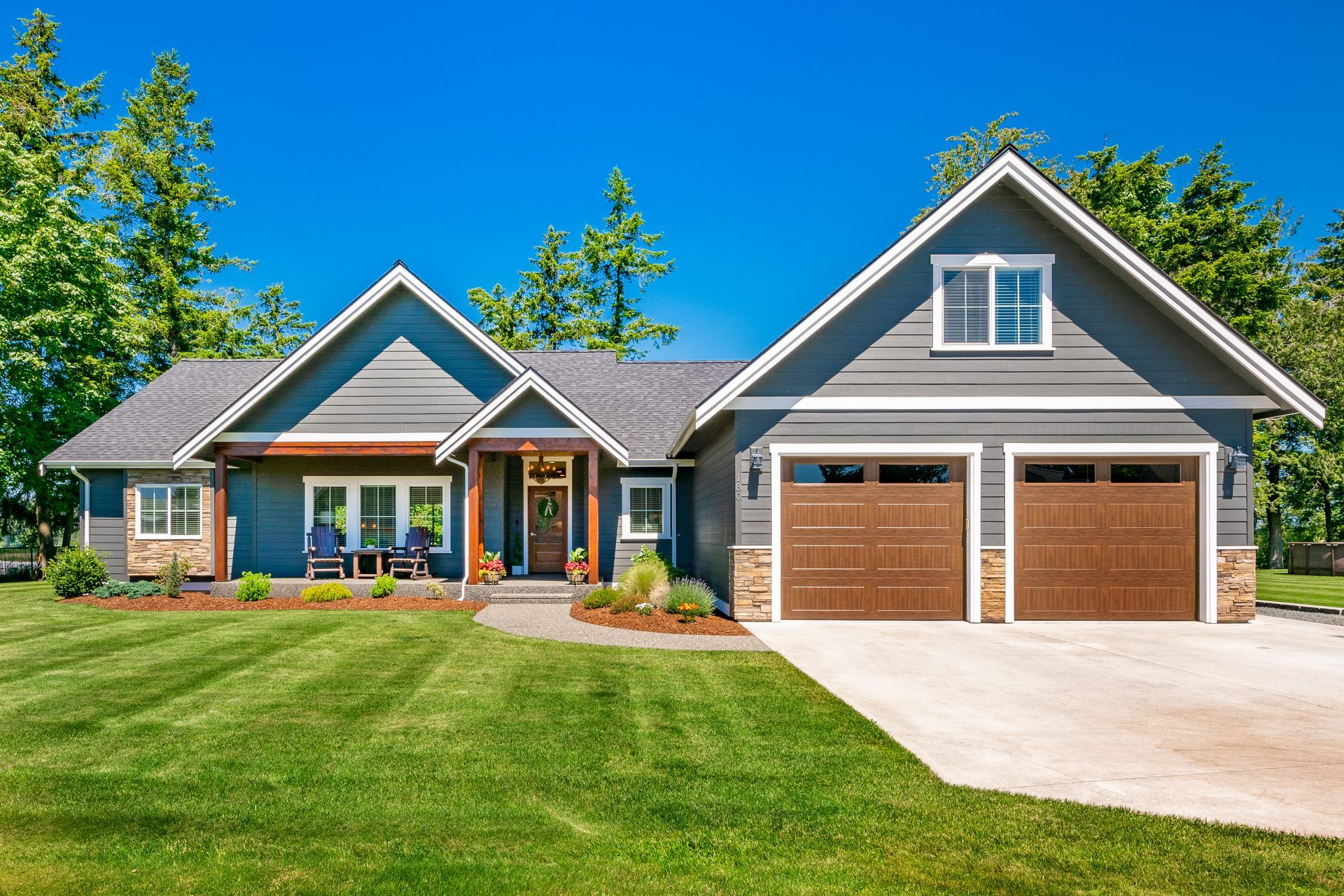 A large house with two garage doors is sitting on top of a lush green lawn.