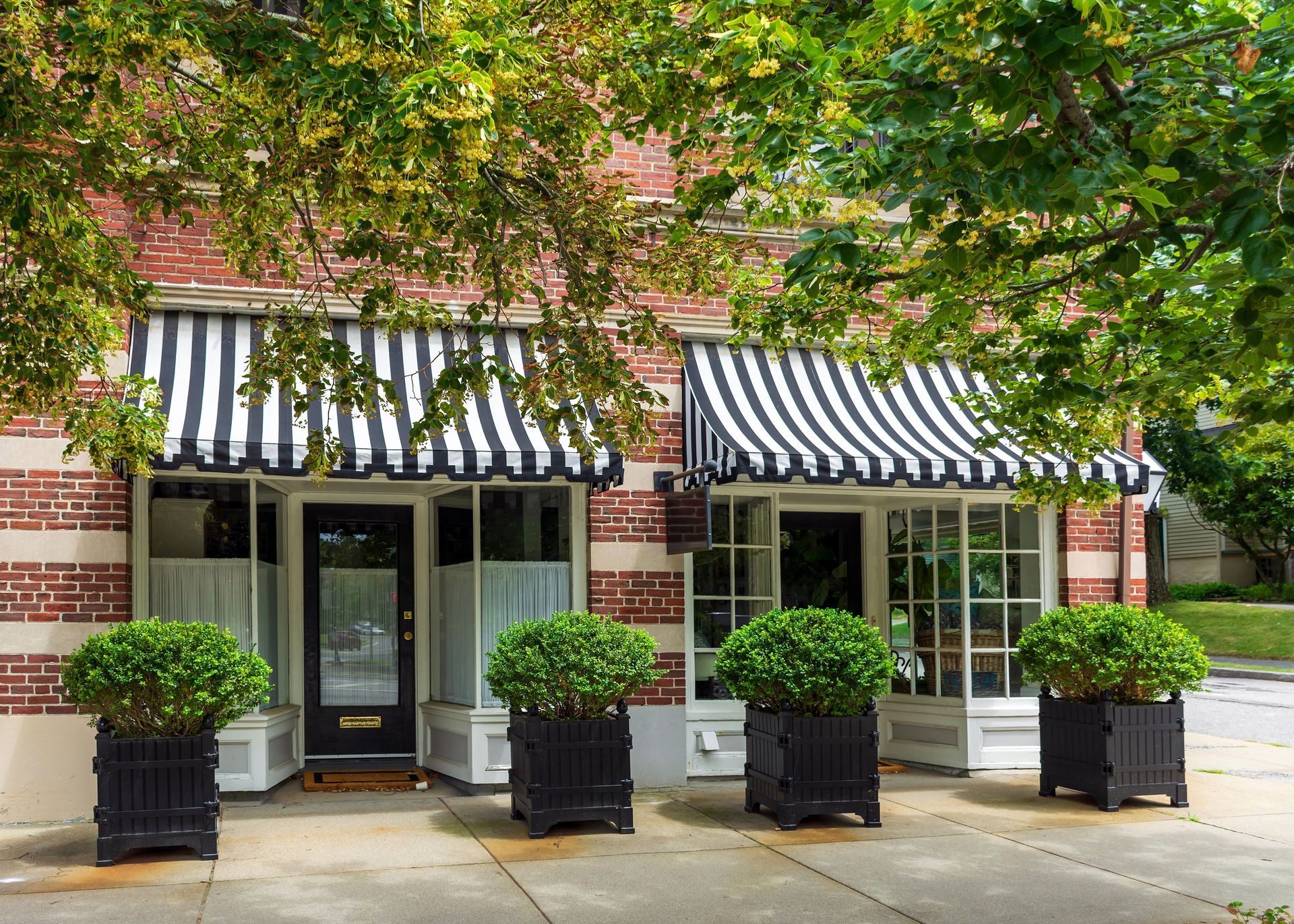 A brick building with a black and white striped awning over the door.