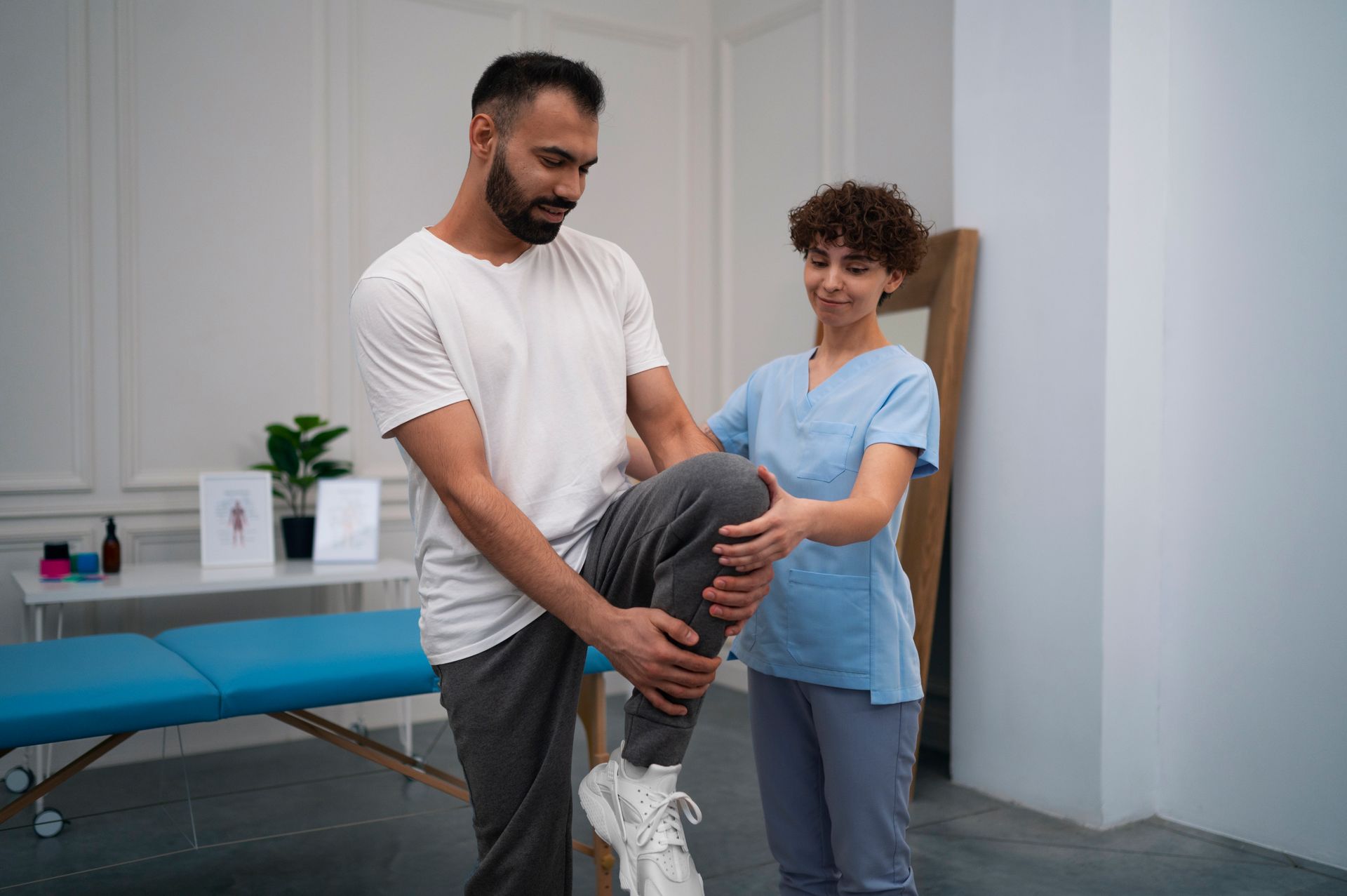 A woman is helping a man stretch his leg.
