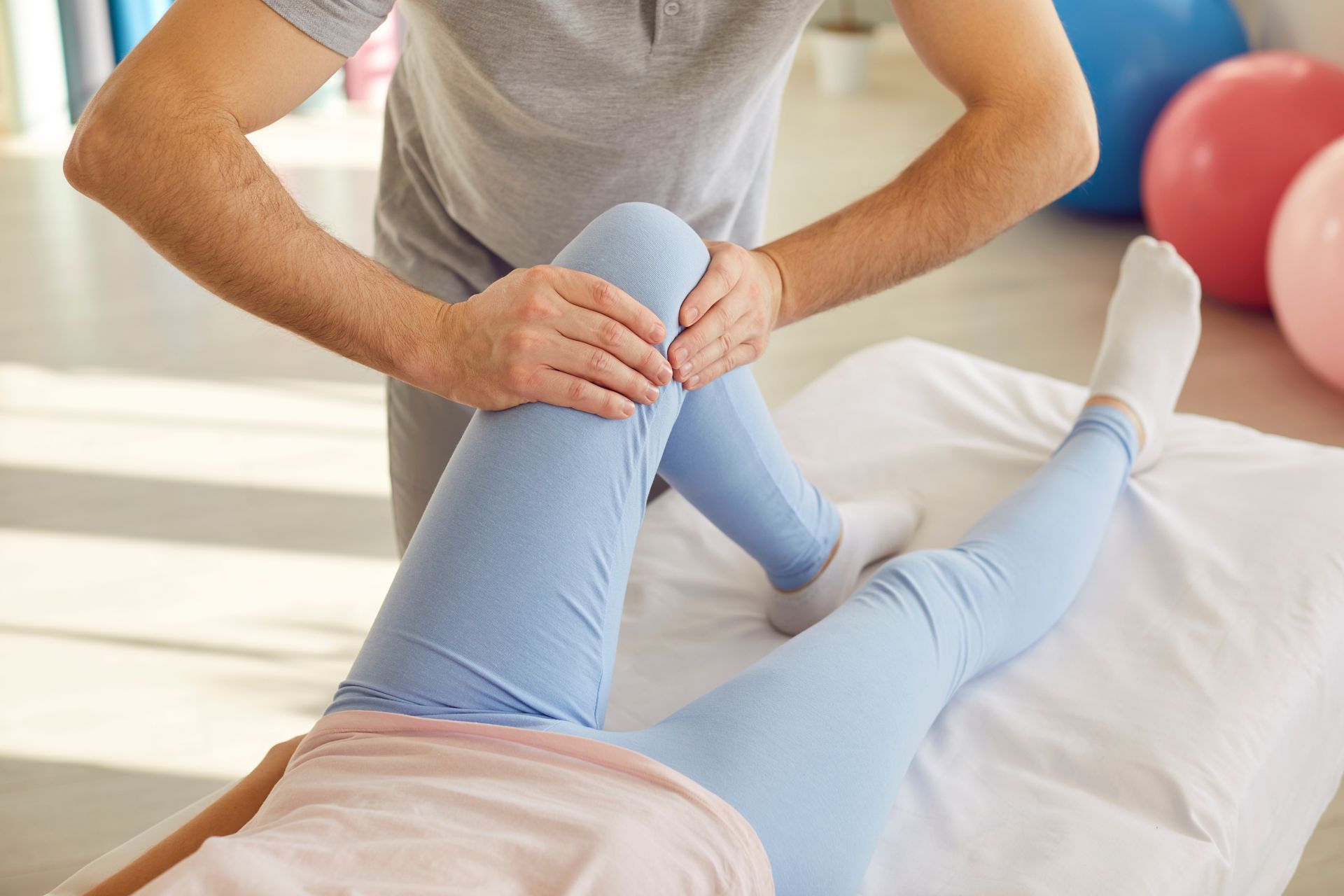 A man is stretching a woman 's leg on a bed.