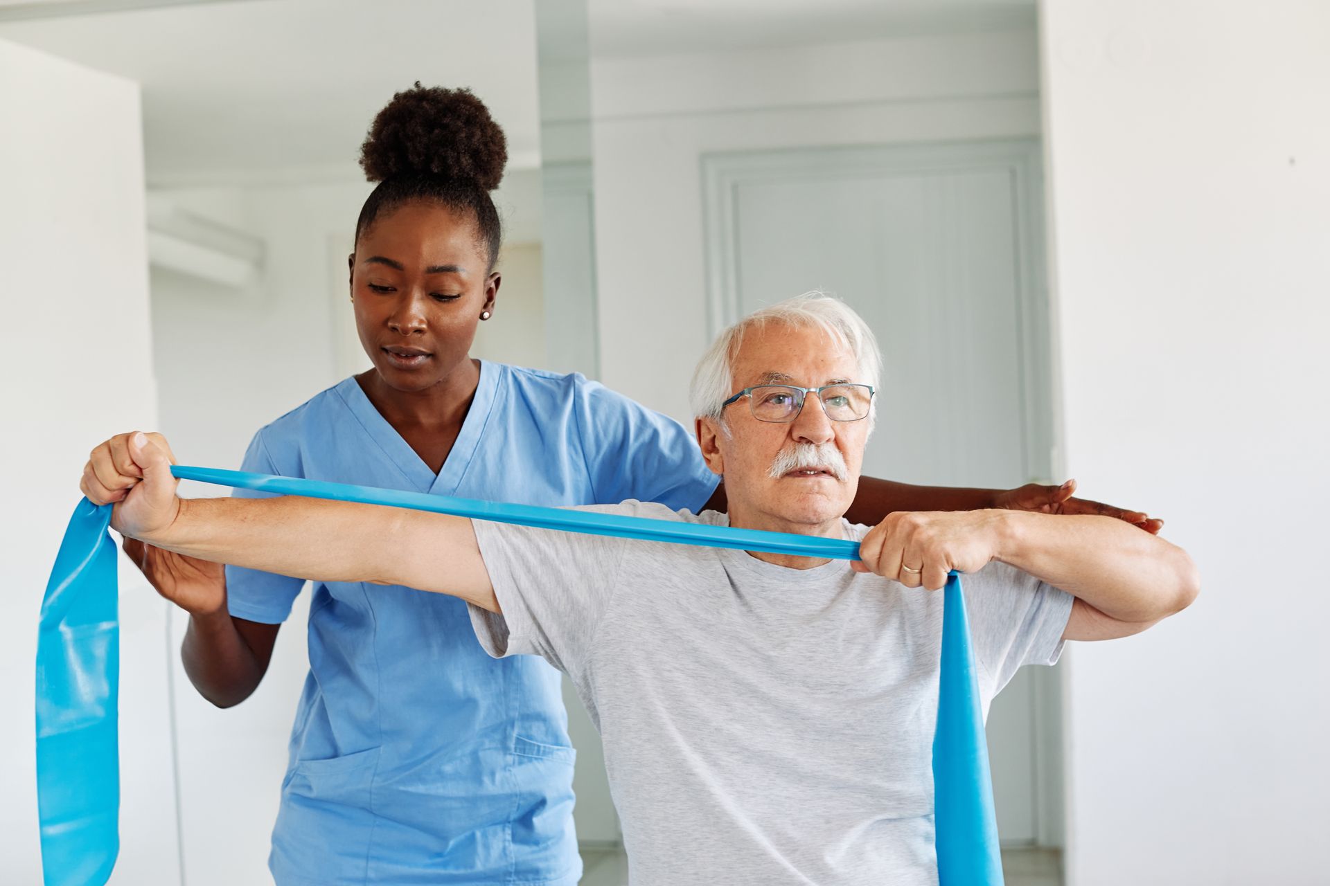 A nurse is helping an elderly man with a resistance band.