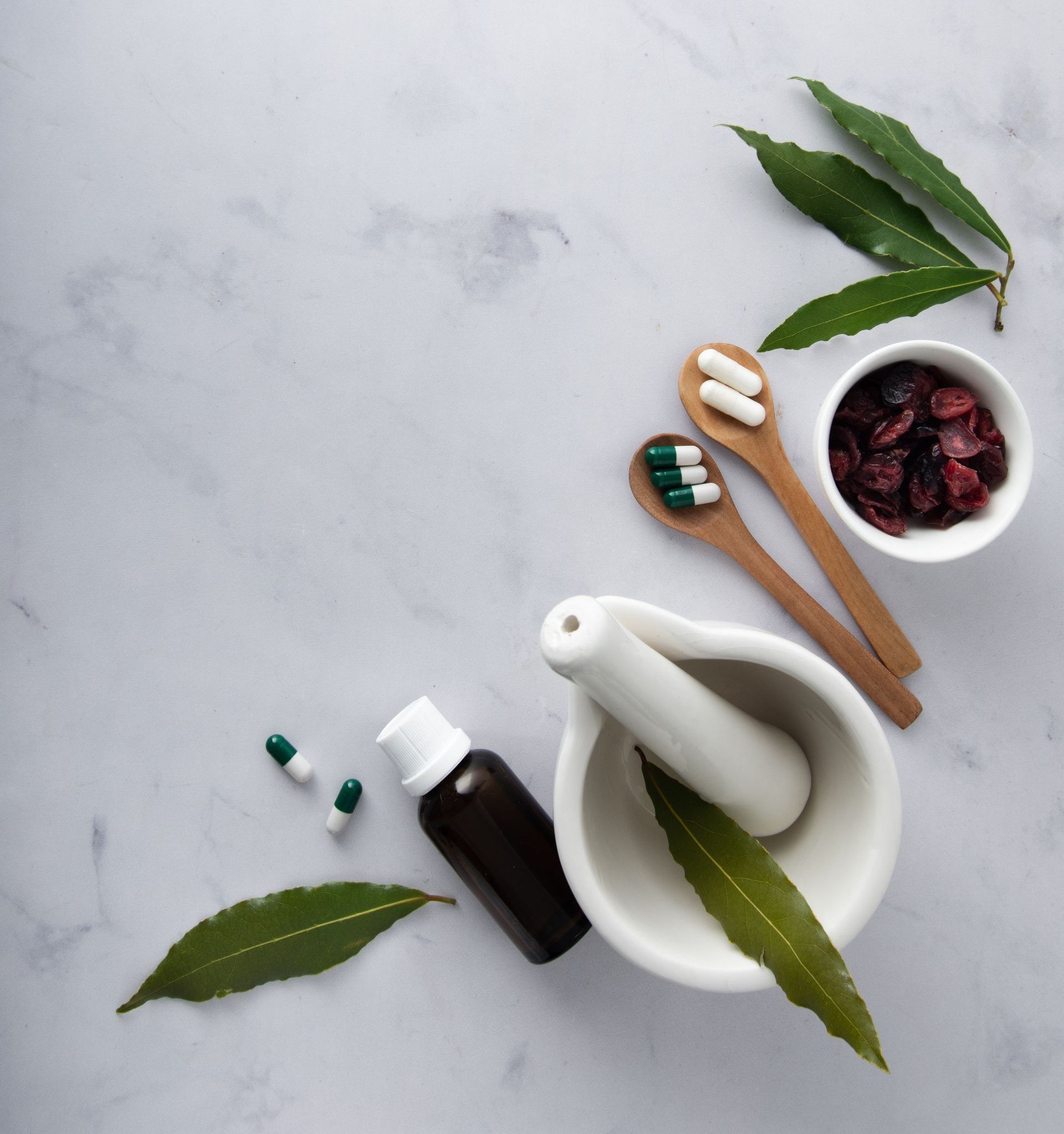 A mortar and pestle surrounded by pills and leaves