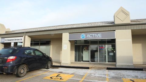 A black car is parked in front of a building.