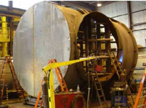 A large metal object is being built in a factory.