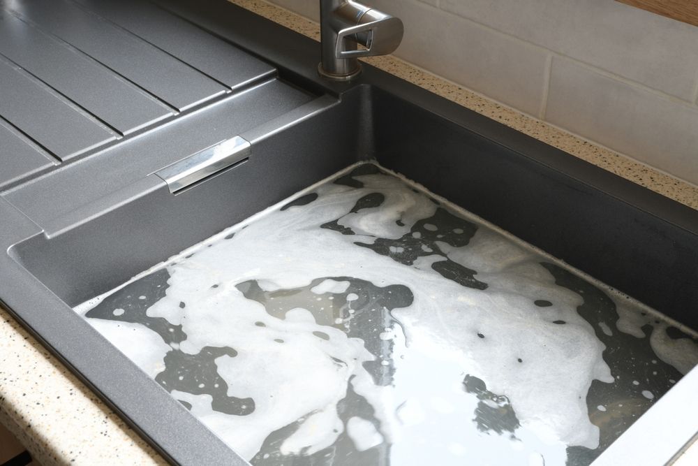 A Gray Kitchen Sink Filled with Soapy Water — Hills 2 Ocean Plumbing in Iluka, NSW