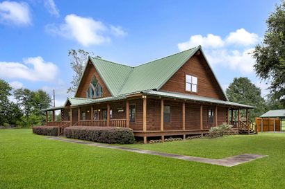 A large log cabin with a green roof and a large porch