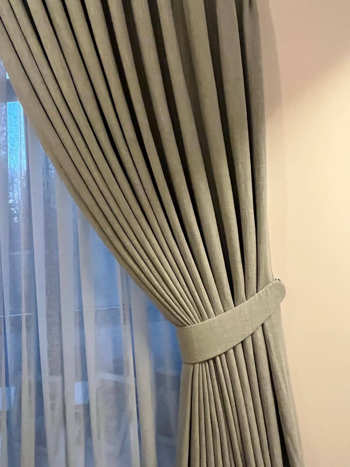 Beige curtains tied back beside a sheer white curtain near a window