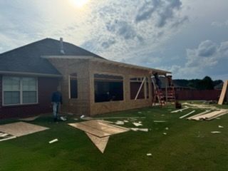 Construction of an outdoor sunroom attached to a house. Framing is up, some siding is in place.